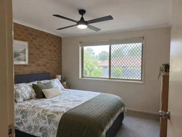Ceiling fan with light in a bedroom with brick feature wall and window in Wyong